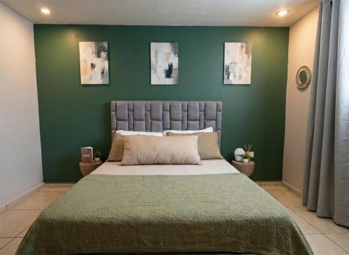 a bedroom with a large bed with a green wall at Departamento céntrico en Aguascalientes cerca del Templo San Antonio - DS2 in Aguascalientes