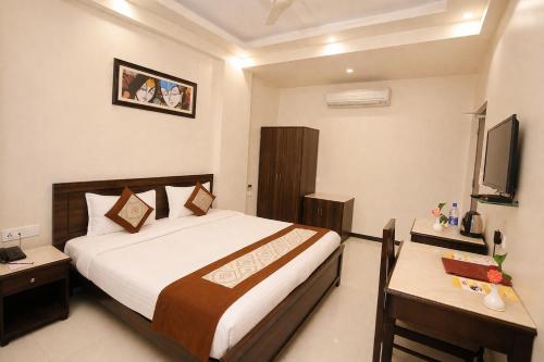 a bedroom with a bed and a desk and a television at Platinum Royal Excellency in Udaipur