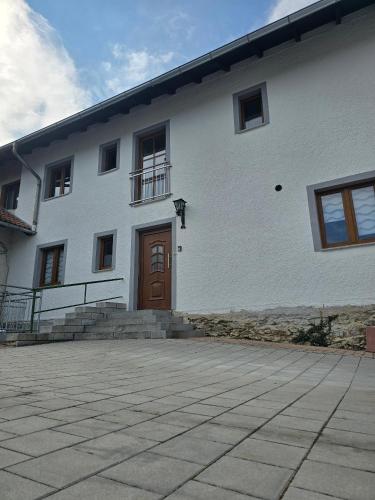 a white building with a brown door and stairs at Ferienwohnung Wilde Hilde inklusive aktivCARD in Arrach