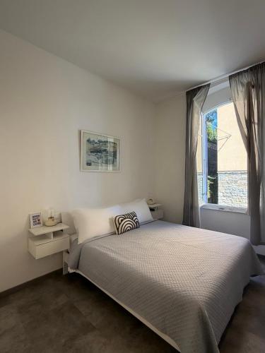 a white bedroom with a bed and a window at Le Finestre Veneris in Portovenere