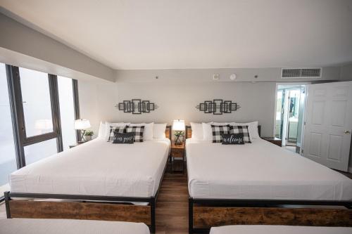 two beds in a room with white walls and windows at Stay Together Suites - Penthouse On The Strip Sleeps 20 - NO RESORT FEE in Las Vegas