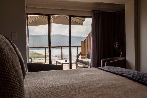 a bedroom with a bed and a view of the ocean at Interlaken Guest House in Wilderness