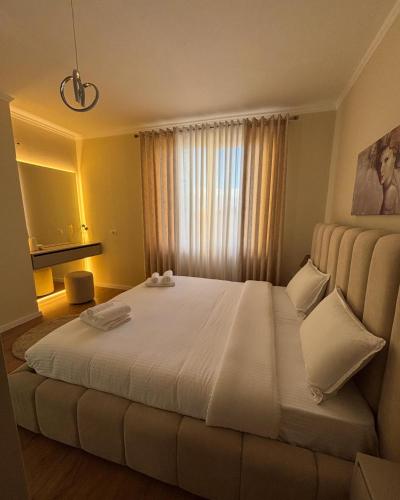 a bedroom with a large white bed with a window at E&O Apartment in Pogradec
