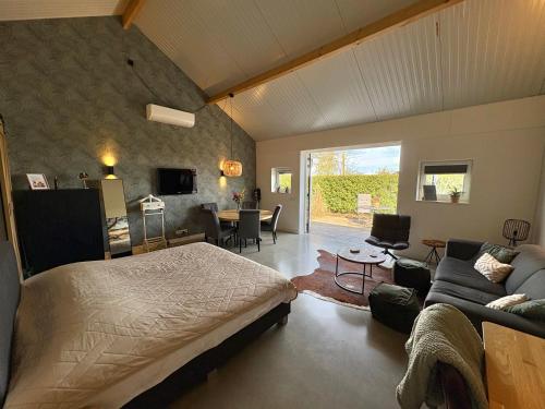 a bedroom with a bed and a living room at Weidezicht Soest, beauty & wellness en rust & natuur in Soest