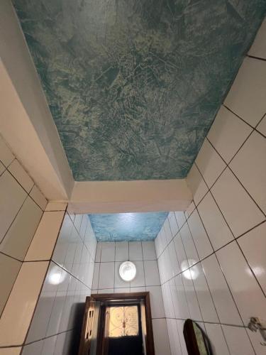 a room with a ceiling with a painting on it at Makepe Bungalow Style in Douala