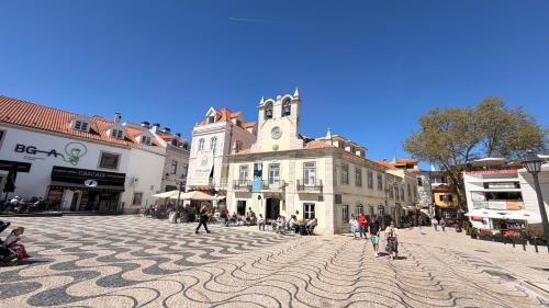 a cobblestone street in a town with a clock tower at Spacious studio apartment in the heart of Cascais historic center in Cascais