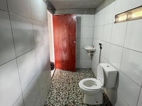 a bathroom with a toilet and a sink and a red door at Diva sunset garden in Senaru