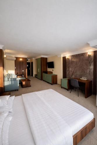 a bedroom with a large white bed and a desk at Hotel President in Arad