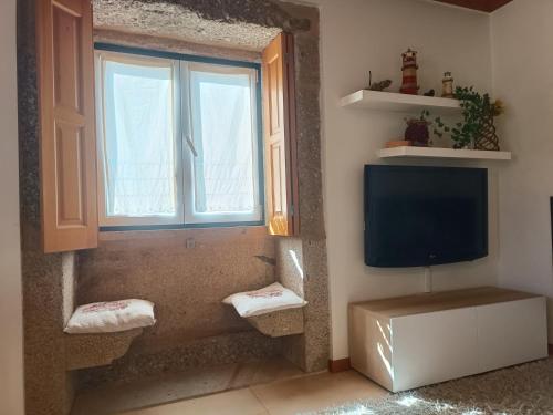 a bathroom with a tv and a window and towels at Casa do Terreiro in Beiral do Lima