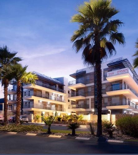 a building with palm trees in front of it at דיויד רזידנט & ספא - by Desert 360 Mountain & sea view in Eilat
