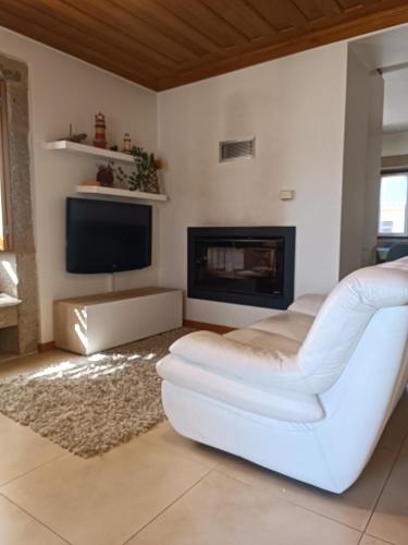 a living room with a white couch and a fireplace at Casa do Terreiro in Beiral do Lima