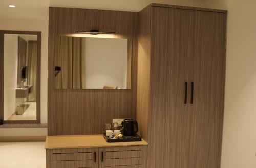 a room with a cabinet with a microwave and a mirror at Kongu Residency in Karūr