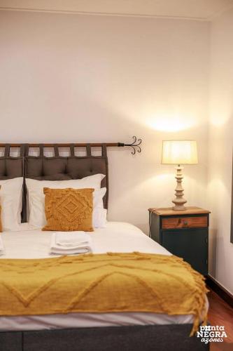 a bedroom with a bed with a yellow blanket and a lamp at Angra Soul 1 - By PontaNegraAzores in Angra do Heroísmo