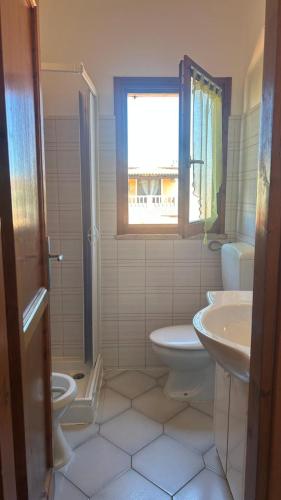 a bathroom with a sink and a toilet and a window at Casa Rita in San Teodoro