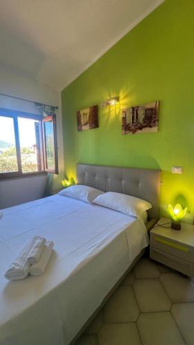 a bedroom with a large white bed with a green wall at Casa Rita in San Teodoro