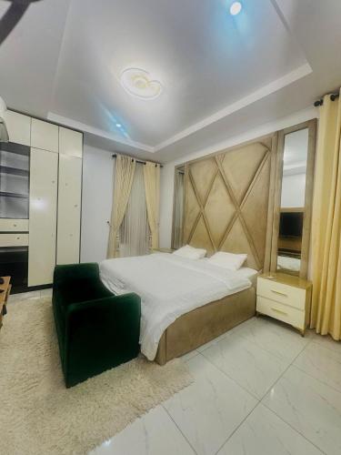 a bedroom with a large bed and a green chair at The Jimi Stay in Maiyegun