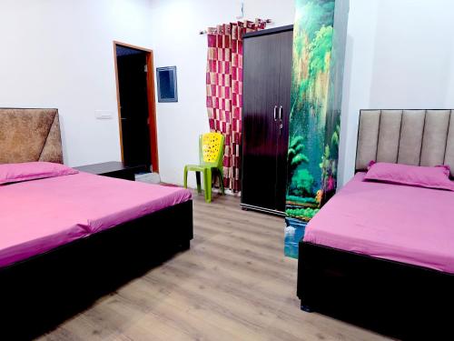 a room with two beds and a yellow chair at Hotel JK in Hanumāngarh