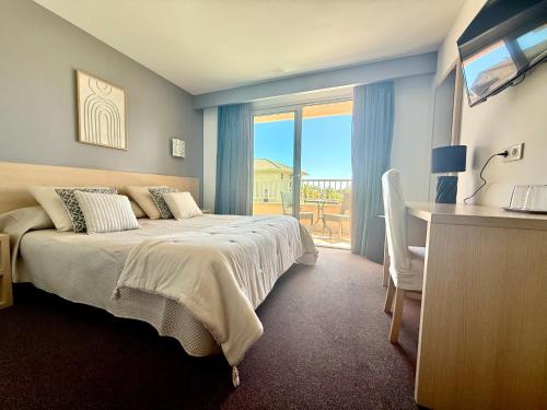 a bedroom with a bed and a desk and a window at Hôtel Restaurant L' Empereur in Aléria