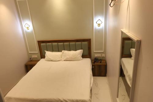 a bedroom with a bed with white sheets and a mirror at Aachman Restaurent in Bulandshahr