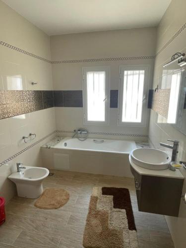 a bathroom with a tub and a toilet and a sink at Villa D'or in Ḩammām al Ghazzāz
