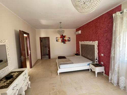 a bedroom with a bed and a red wall at Villa D'or in Ḩammām al Ghazzāz