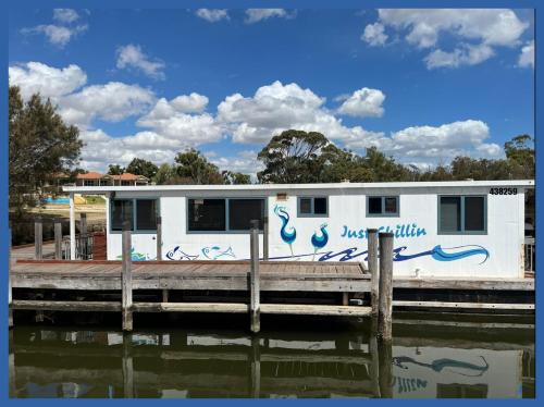 a house with graffiti on it next to a dock at Mandurah Houseboat Just Chillin in Mandurah