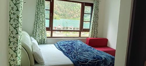a bed in a room with a window and a bench at Gurez knights in Kanzalwan