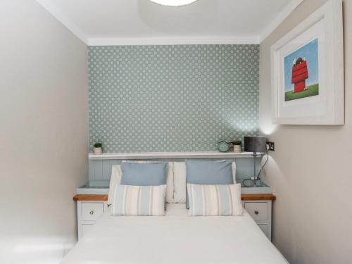 a bedroom with a white bed with two pillows at Firefly Cottage in Cirencester