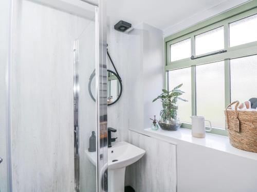 a white bathroom with a sink and a mirror at Firefly Cottage in Cirencester