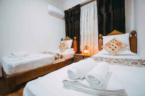 a hotel room with two beds with towels on them at Royal Bukhara hotel in Bukhara