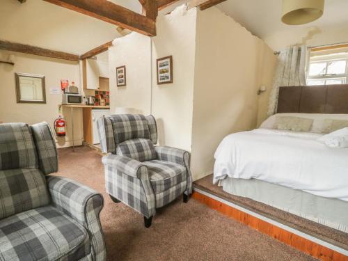 a bedroom with a bed and two chairs at Mews Cottage 5 in Keswick