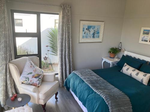 a bedroom with a bed and a chair and a window at Shelley Cove in Stompneusbaai