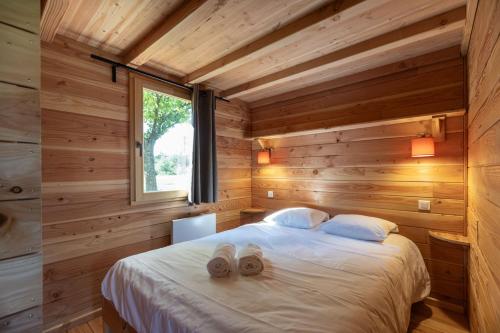 a bedroom with wooden walls and a bed with two towels at Huttopia Versailles in Versailles