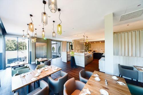 a dining room with tables and chairs and a kitchen at See und Sporthotel Ankum mit Lakeside Apartments in Ankum