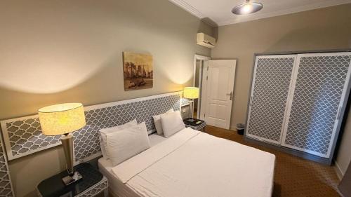 a bedroom with a white bed and two lamps at Dream Royal Residence in 6th Of October