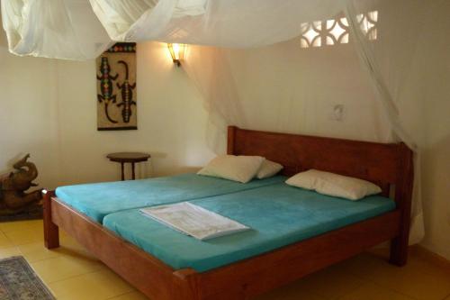 a bedroom with a bed with blue sheets and a window at Villa Madinina in Diani Beach