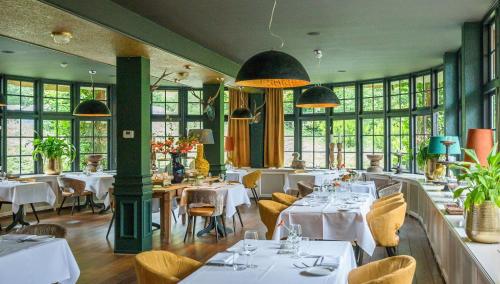 a restaurant with white tables and chairs and windows at Restaurant & Hotel Hoog Holten in Holten