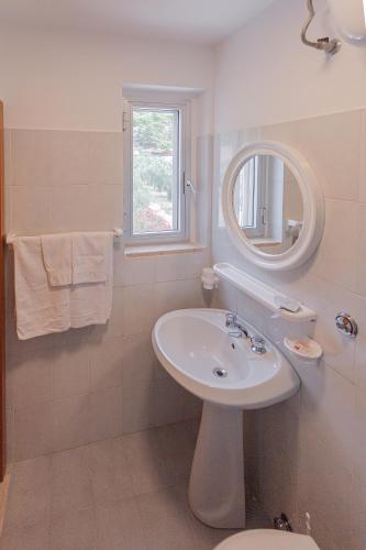 a white bathroom with a sink and a mirror at Casaverde Gargano in Mattinata