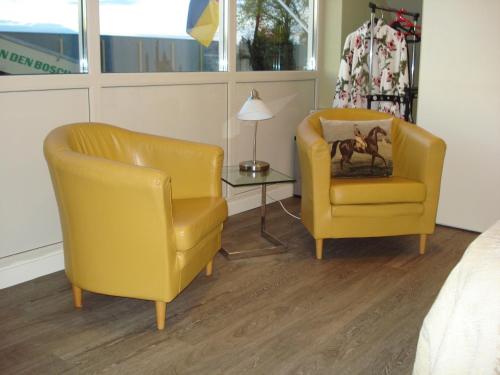two yellow chairs and a table in a bedroom at B & B Leudal in Haelen