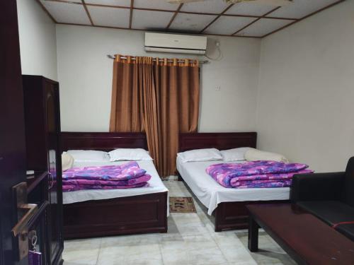 two beds sitting in a room with a table at Hotel Mohsin Plaza in Sreemangal