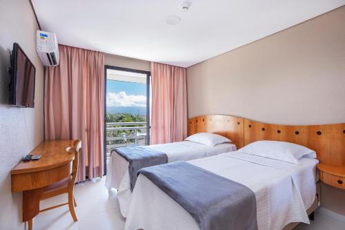 a hotel room with two beds and a window at Hotel Aojesp in Caraguatatuba