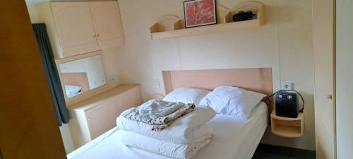 a small bedroom with a bed with white sheets at Stacaravan in De Pol