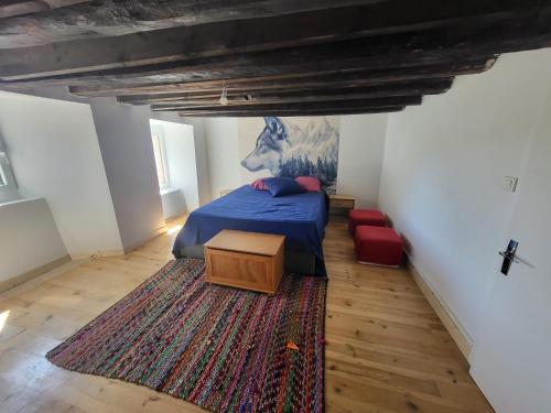 a bedroom with a blue bed and a rug at Maison ferme équestre du Ténéré in Saint-Jean-Lachalm
