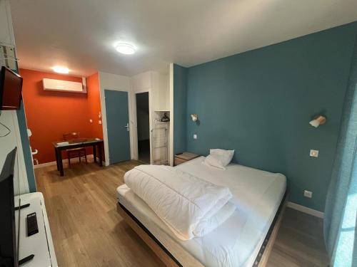 a bedroom with a white bed and a blue wall at Les gîtes de Mazélise in Mazerolles