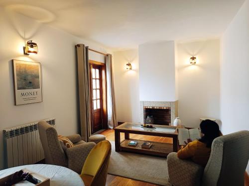 a woman sitting on a couch in a living room at Casa Vitral - Stained Glass House in Miranda do Douro