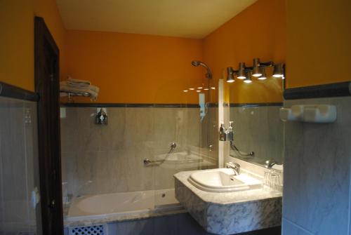 uma casa de banho com um lavatório, uma banheira e um espelho. em Hotel Casa Julián em Peñamellera Alta