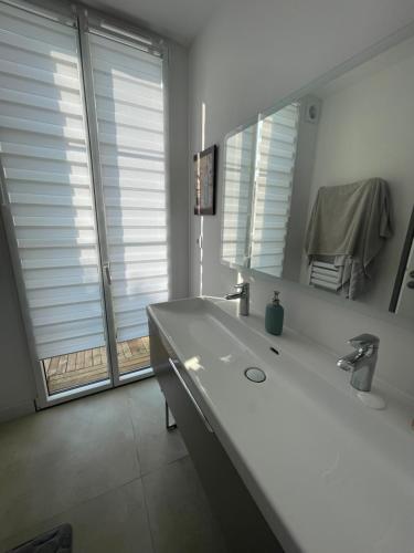 a white bathroom with a sink and a mirror at Arcachonnaise 5 chambres, 500M de la plage et 6 vélos à disposition in Arcachon