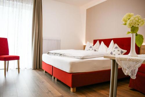 a bedroom with a bed and a vase of flowers on a table at Pension Tannenhof in Laces