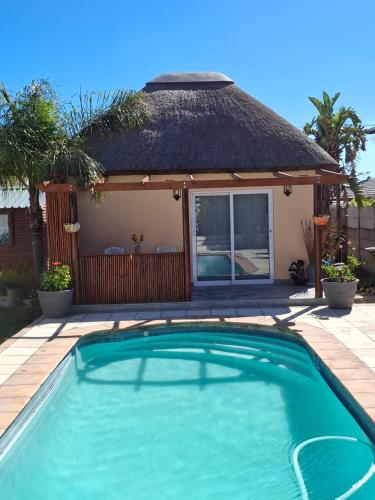a swimming pool in front of a house at Fynbos & Pinot Guest Cottage in Kuilsrivier