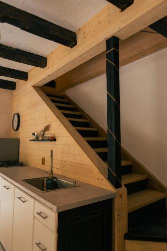 a kitchen with a sink and a wooden staircase at Cabana Murmur -Riverside- in Valea Ierii